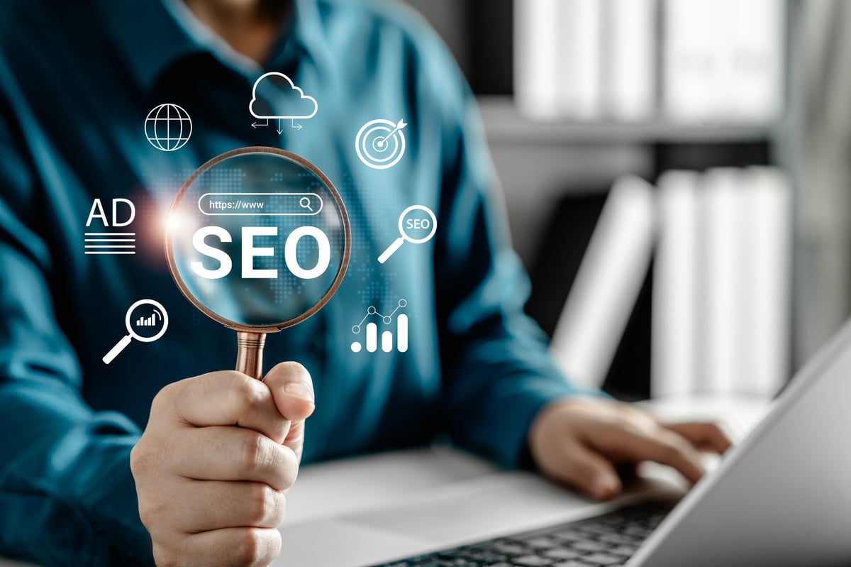 Businesswoman using magnifying glass to analyze SEO and digital marketing strategy on laptop, search engine optimization, online advertising, and website traffic analysis in modern office.